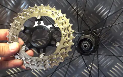 En hand håller en cykelkassett redo att byta ut den på bakhjulet.