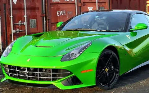 Jaskrawozielone Ferrari F12 Berlinetta z czarnymi felgami, zaparkowane przed czerwonym kontenerem.