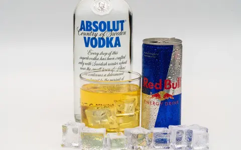 Szklanka z drinkiem, puszka Red Bulla i butelka wódki Absolut – klasyczny energetyk z alkoholem.