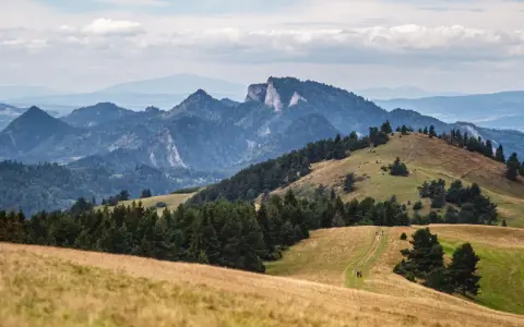 Malowniczy krajobraz górski, idealny na szczawnica trasę. W oddali skaliste szczyty, bliżej zielone wzgórza i ścieżka dla turystów.