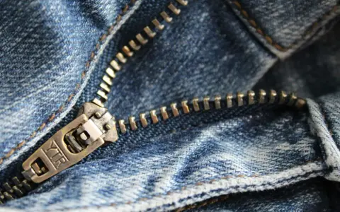Primer plano de una cremallera de jeans. Aprende como arreglar una cremallera rota para que tus pantalones vuelvan a funcionar.