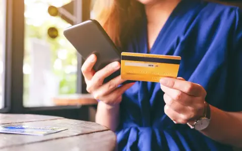 Frau hält Smartphone und goldene Kreditkarte für Online-Shopping.