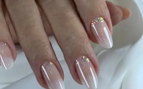 Dłonie z eleganckim baby boomer z brokatem. Delikatny manicure podkreśla naturalne piękno.