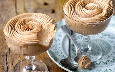 Due coppe di deliziosa mousse al caffè, guarnite a spirale, su un piatto decorato.