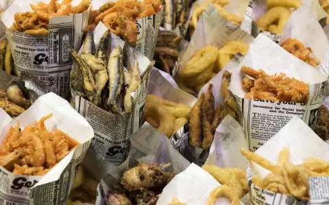 Una variedad de fritura de pescado, incluyendo camarones, boquerones y calamares, servidos en conos de papel.