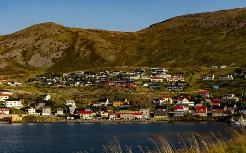 Kolorowe domy nad fiordem, w tle górzysty krajobraz. Nordcamp Norwegia, malownicza wioska rybacka.