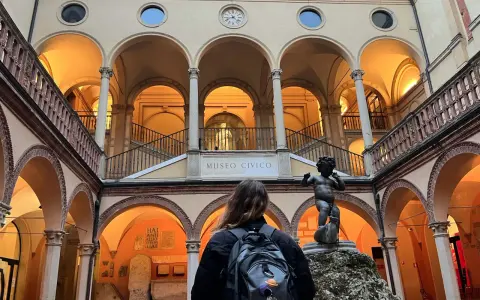 Cortile del Museo Civico, uno dei musei da visitare a Bologna, con una statua di putto e una persona con zaino.