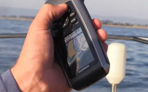 Main tenant une carte GPS Garmin sur un bateau, naviguant sur l'eau.