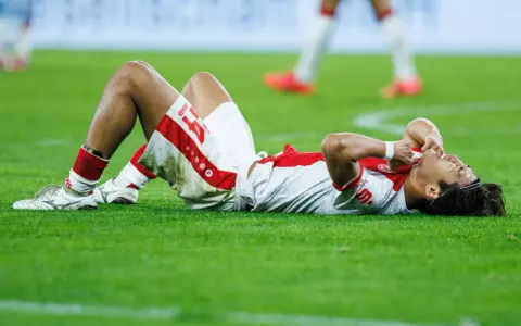 Fußballer liegt erschöpft auf dem Rasen, die Hände im Gesicht. Nach einem harten Spiel braucht er Regeneration.