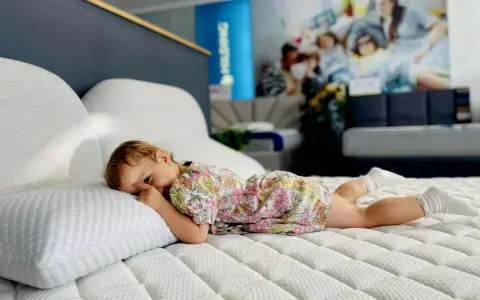 Małe dziecko w kwiecistej sukience leży na materacu. Czy lateks jest szkodliwy? Ten materac wygląda na bardzo wygodny.