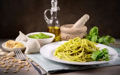 Pyszny makaron z pesto ze słoika, podany z bazylią, czosnkiem, parmezanem i orzeszkami pinii.