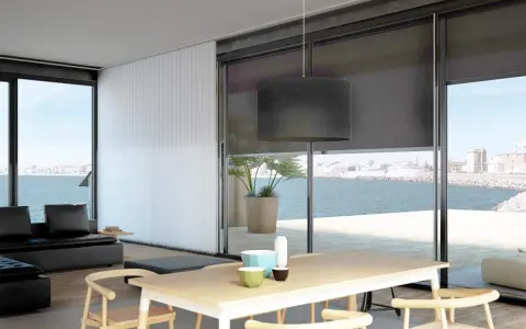 Comedor moderno con vistas al mar, decorado con estores Bandalux que controlan la luz.