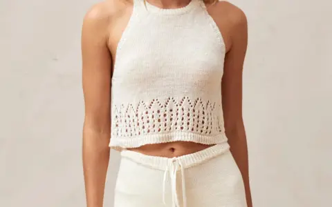 Top a ganchillo blanco con detalles calados en el bajo.