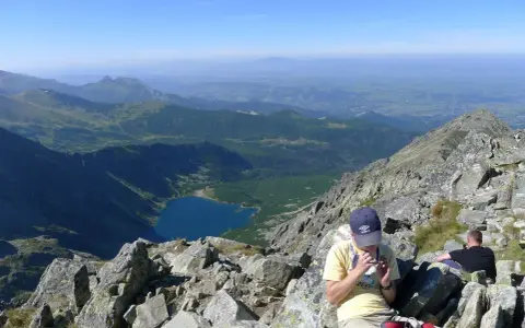 Widok na Tatry z żlebu Kulczyńskiego. W dole jezioro, na pierwszym planie odpoczywający turyści.