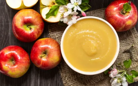 Frische Äpfel und eine Schüssel mit selbstgemachtem Apfelmus, garniert mit Apfelblüten. Ein Genuss für alle Sinne!