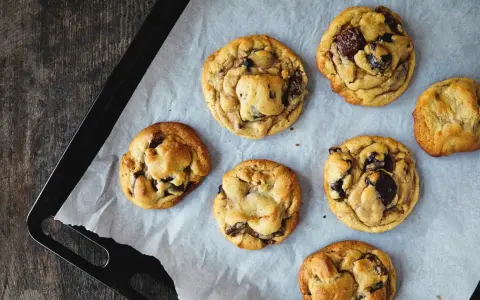 Sept cookies américains aux pépites de chocolat, tout juste sortis du four, prêts à être dégustés. Une recette de cookie américain parfaite !