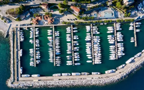 Widok z lotu ptaka na port w Chorwacji, pełen białych jachtów i łodzi zacumowanych w turkusowej wodzie.