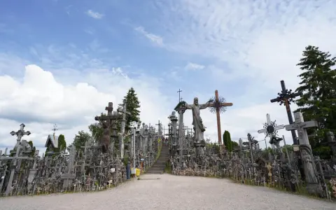 A vast mountain of crosses, with a statue of Jesus at its peak, stands under a cloudy sky.