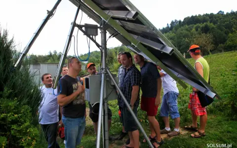 Uczestnicy kursu fotowoltaika montują panele słoneczne. Grupa mężczyzn przygląda się konstrukcji.
