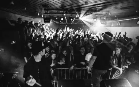 Koncert pro8l3m art brut 2 utwory. Tłum szaleje, artyści na scenie, światła i dym tworzą niepowtarzalny klimat.