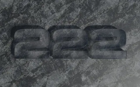 Trzy przezroczyste cyfry 2, ułożone obok siebie na kamiennym tle. Liczba 2222 ma znaczenie w numerologii, symbolizując równowagę i harmonię.