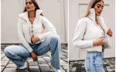 Elegancka stylizacja: jak nosić kamizelkę puchową z jeansami i swetrem. Kremowa kamizelka puchowa, biały sweter z warkoczami, szerokie jeansy i białe botki.