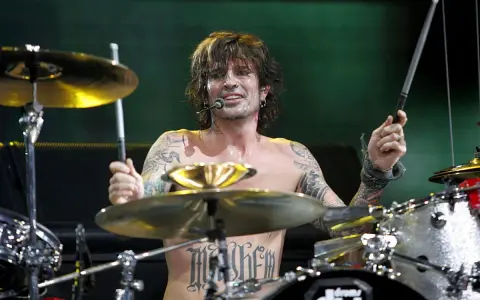 Tommy Lee, batteur du groupe, frappe sur sa batterie, torse nu, tatoué, en plein concert.
