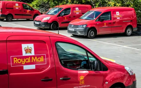 Czerwone furgonetki Royal Mail Polska zaparkowane na placu.
