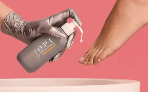 Gloved hand dispenses OPI Nature Strong Pedi Soak, preparing to soak feet for a luxurious pedicure.
