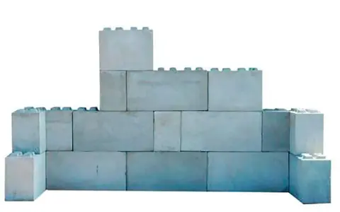 Una pared de bloques grises, apilados de forma irregular, simula un castillo de juguete.
