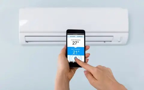 Mano ajustando la temperatura del aire acondicionado desde el móvil, facilitando conectar aire acondicionado a wifi para control remoto.