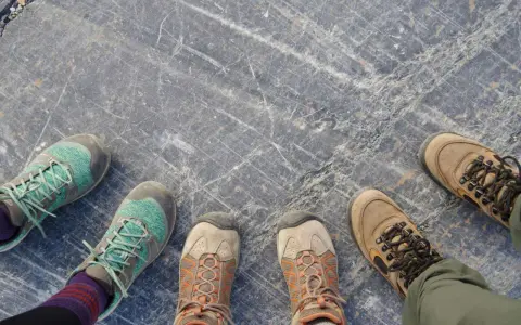 Vier Paar Wanderschuhe auf grauem Steinboden. Die Frage "wie fallen Meindl Schuhe aus?" bleibt offen, da keine Meindl-Schuhe zu sehen sind.