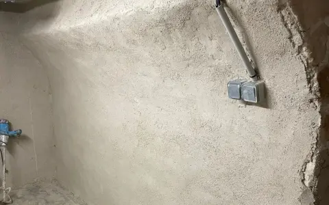 Murs bruts avec prises électriques et tuyauterie, étape clé pour savoir comment assainir une maison.
