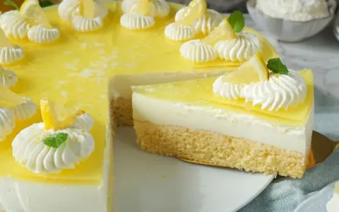 Erfrischende joghurt-torte mit biskuitboden, dekoriert mit Zitronenspalten und Sahnetupfern.