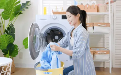 Une femme charge du linge bleu dans une machine à laver. Le cycle de rincage de la machine à laver est terminé.