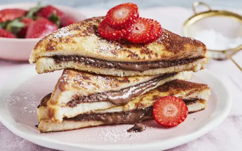 Gestapelte French Toast mit Nutella, bestäubt mit Puderzucker und garniert mit Erdbeeren. Ein süßer Genuss!