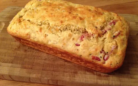 Un délicieux cake aux lardons, doré et moelleux, prêt à être dégusté sur une planche en bois.