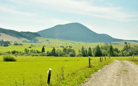 Zielone pola i lasy Beskidu Niskiego, z charakterystycznym, łagodnym kształtem najwyższego szczytu w tle.