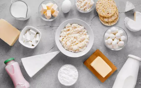 Różnorodne produkty bogate w wapń: mleko, sery, jogurt, masło, jajko i wafle ryżowe.