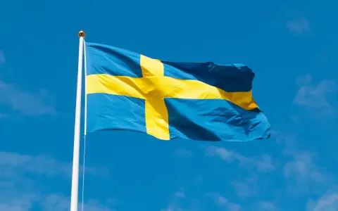 Svenska flaggan vajar i blå himmel. Dess korsdesign har en lång svenska flaggan historia, symboliserande nationens arv.