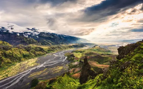 Spektakularny krajobraz Islandii z rzeką i ośnieżonymi górami. Warto zobaczyć, choć islandia ceny mogą być wysokie.