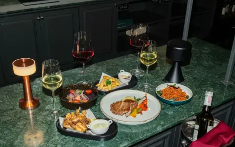 Elegancka kolacja z daniami i winem. Czy to chardonnay, jakie to wino? Obok kieliszki z białym i czerwonym winem, mięso, frytki i sałatka.