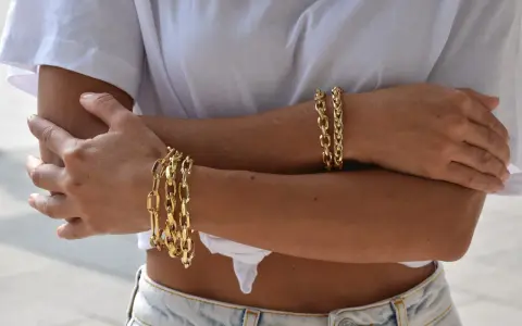 Bracciali in oro 18 carati, più brillanti e preziosi rispetto all'oro 9 carati, adornano le braccia di una donna.