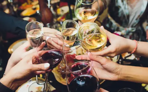 Ręce wznoszą kieliszki z winem, białe i czerwone, do toastu. Rozpoczyna się radosne świętowanie i trawienie alkoholu.