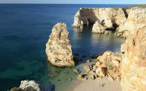 Felsformationen und eine kleine Bucht bei Ilha de Tavira. Das klare Wasser schimmert türkis.