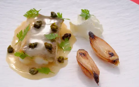 Delicioso lenguado a la meunière con alcaparras, perejil, cebollas caramelizadas y una quenelle de crema.
