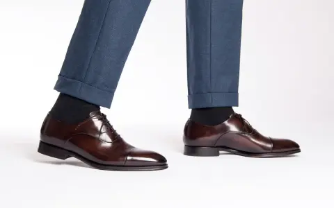 Eleganza senza tempo: un uomo indossa pantaloni blu e scarpe oxford non brogue marroni lucide, perfette per ogni occasione formale.