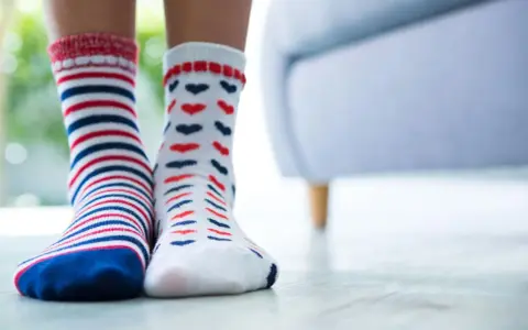 Zwei Paar bunte Socken, gestreift und mit Herzen, warten darauf, mit der richtigen Methode socken sauber bekommen zu werden.
