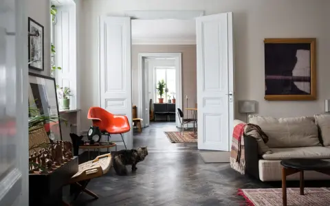 Erika Kangas hem med en katt som smyger förbi en orange stol och en soffa.