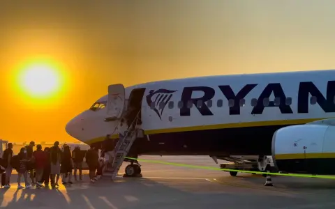 Zachód słońca nad lotniskiem, pasażerowie wsiadają do samolotu Ryanair. Wspaniałe **Ryanair loty z Bydgoszczy** czekają!